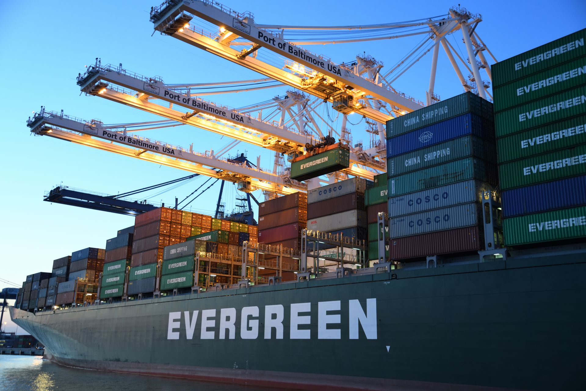 Container ship alongside port cranes at dusk